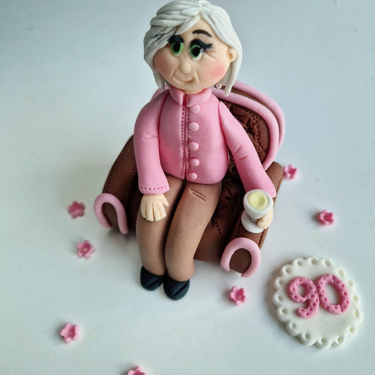 Edible fondant figurine sitting in the armchair cake decoration